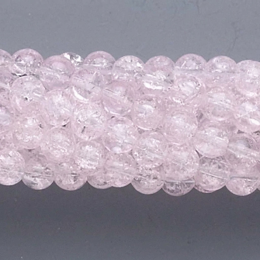 A close-up of a strand of round, faceted light pink beads on a dark gray background.