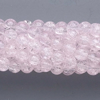 A close-up of a strand of round, faceted light pink beads on a dark gray background.