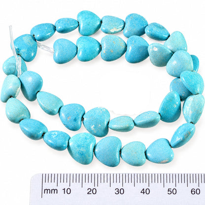 A strand of light blue turquoise heart-shaped beads displayed on a neutral background, with a US quarter coin and a 60 cm ruler included for scale.