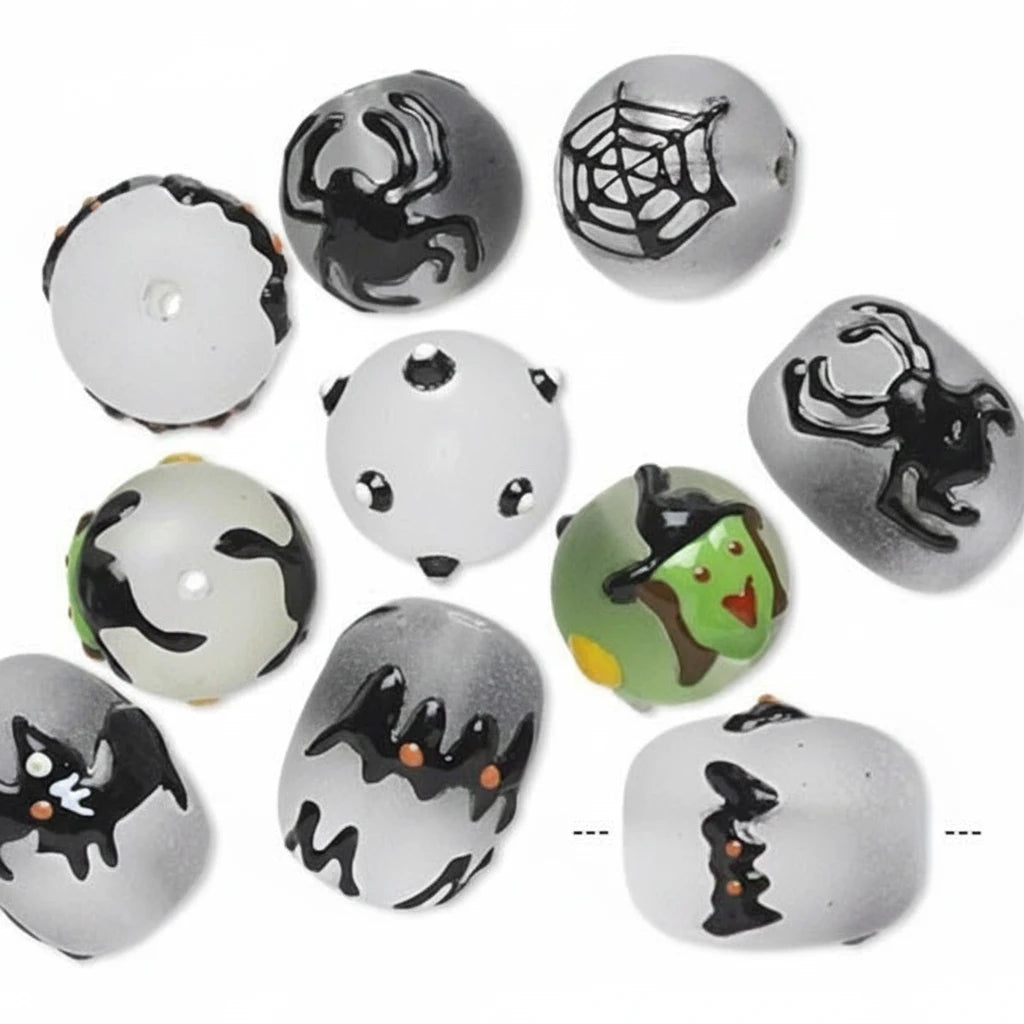 A set of round glass beads with a white base, decorated with various Halloween-themed illustrations including spiders, webs, bats, a spider on a door, a witch, and a cat.