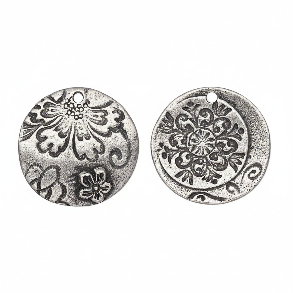 Two round silver-toned metal charms with embossed floral and scroll patterns, shown from both sides on a white background.