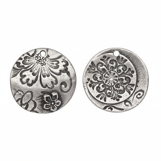 Two round silver-toned metal charms with embossed floral and scroll patterns, shown from both sides on a white background.