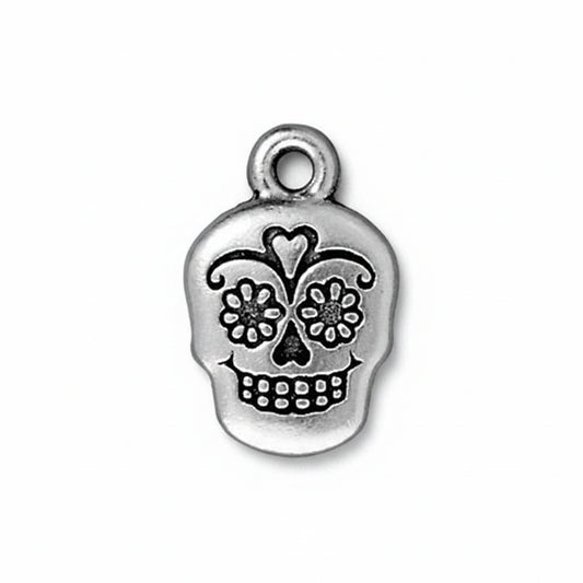 Silver skull charm with floral details on a white background. DAY OF THE DEAD