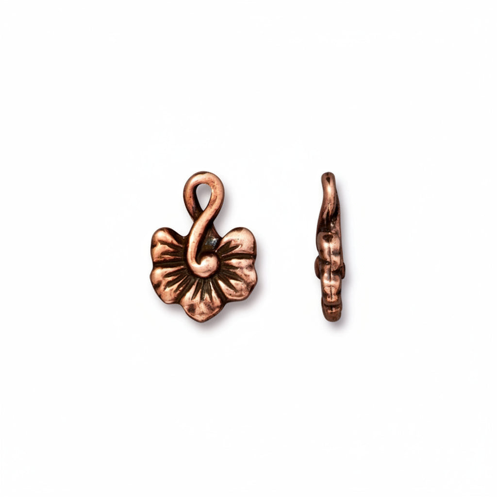 A pair of copper-colored metal flower charms, one shown from the front displaying a five-petal design with a loop at the top, and the other from the side showing its hook shape, on a plain white background.