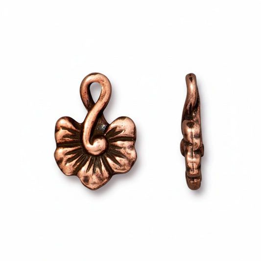 A pair of copper-colored metal flower charms, one shown from the front displaying a five-petal design with a loop at the top, and the other from the side showing its hook shape, on a plain white background.
