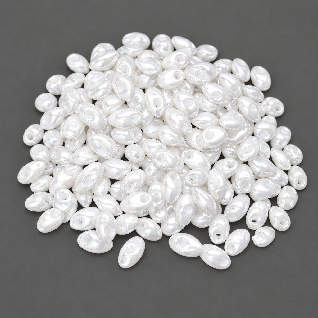 A pile of small, glossy white oval beads with central holes, shown against a dark gray background.