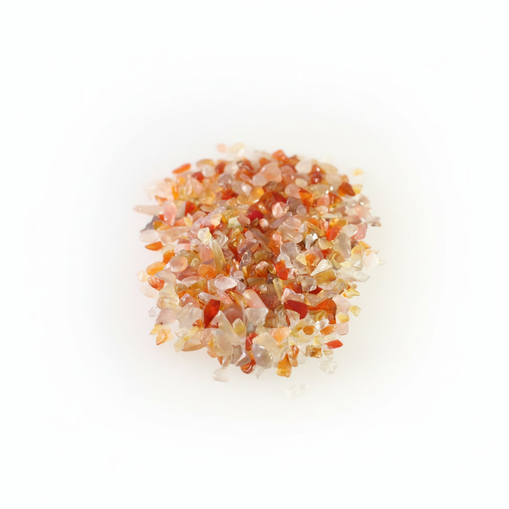 A close-up pile of small polished gemstone chips in translucent shades of orange, red, pink, and clear on a white background.