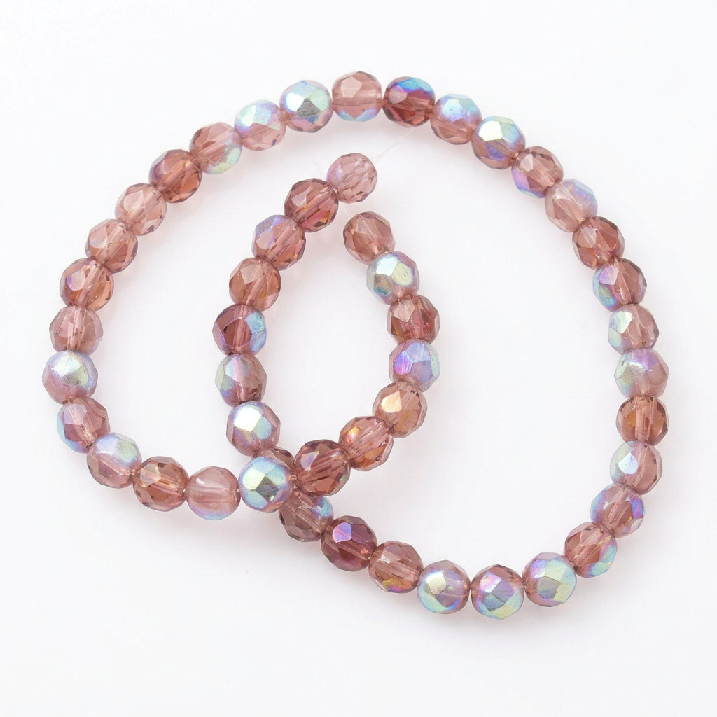 A strand of faceted round beads in a dusty rose-brown color with an iridescent AB finish, shown next to a US quarter for scale on a white background.