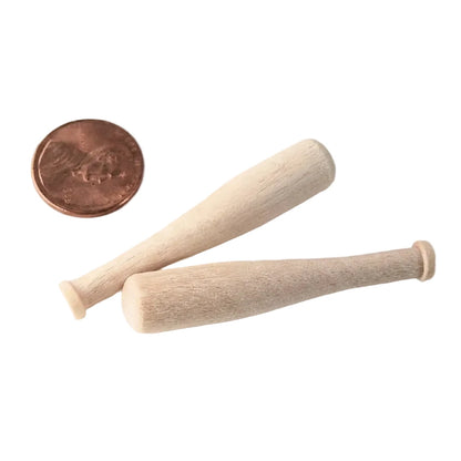 Two miniature unfinished wooden baseball bats shown on a white background with a US penny for scale.