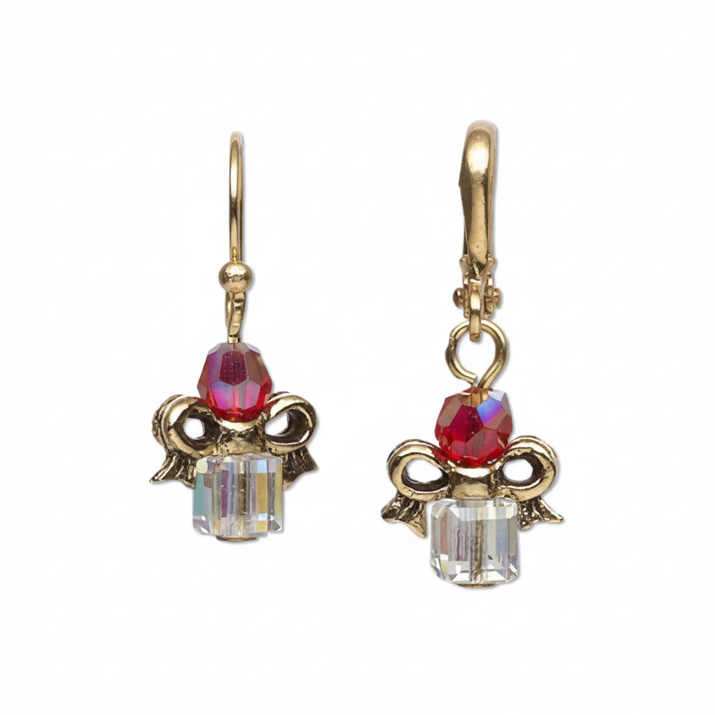 A pair of dangling earrings with gold-tone angel motifs, a faceted pink crystal at the top, and a clear iridescent crystal at the bottom, shown on a white background with '*Sample Only' text below.