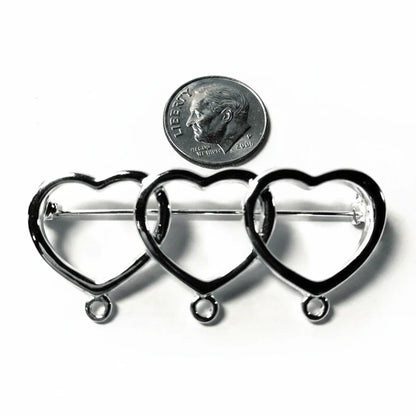 Three silver heart-shaped metal pin frames with loops at the bottom, arranged side by side on a white background with a U.S.