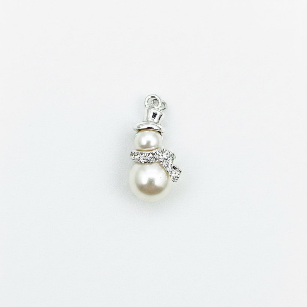 A small snowman pendant charm featuring two cream-colored faux pearls, a silver-tone top hat, and a silver bow with clear rhinestone accents, set against a plain light gray background.
