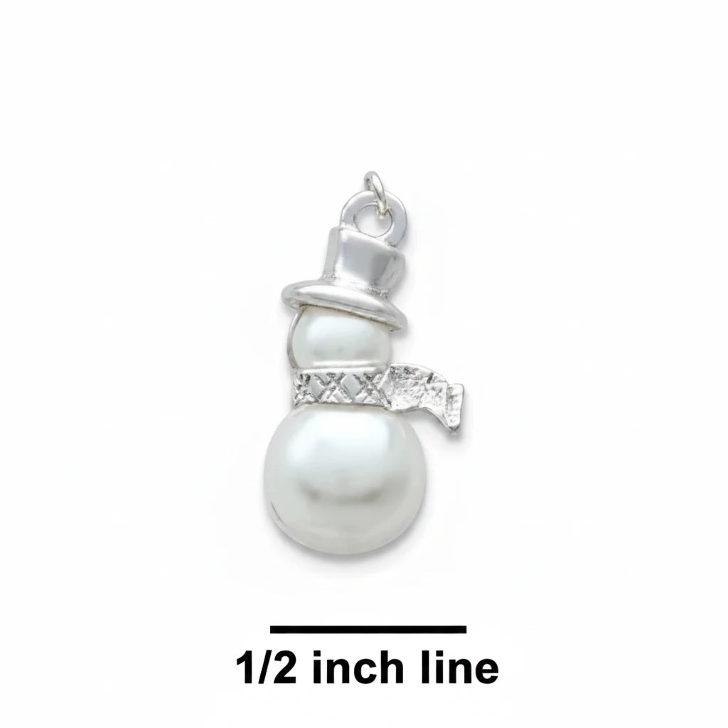 A small snowman charm pendant with a silver-toned hat and scarf and a white pearl-like body, shown on a blue textured background with a size marker reading 1/2 inch line.