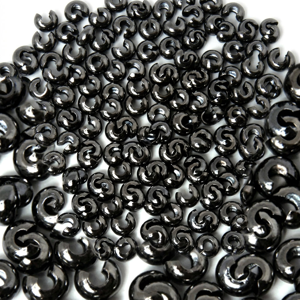A close-up pile of glossy black bead COVERS on a white background.