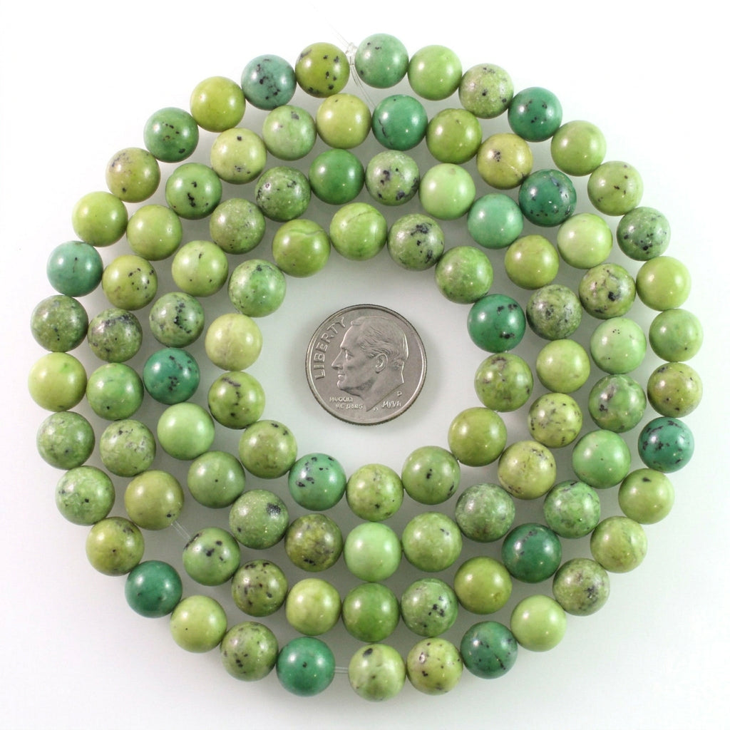 Green stone bead strand with natural speckling and variation, shown on a white background with a coin for scale.