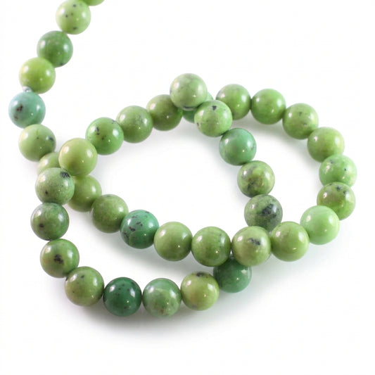 A strand of polished round beads in light to medium green with natural marbling and dark inclusions, arranged on a plain white background.