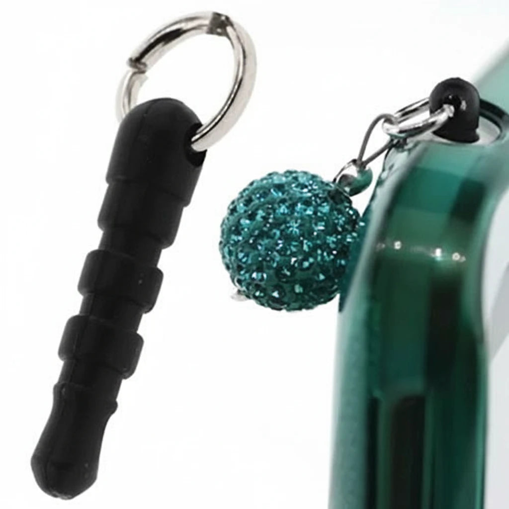 A close-up of a black silicone plug attached to a silver metal key ring, shown next to a green phone case with a sparkling teal glitter ball charm.