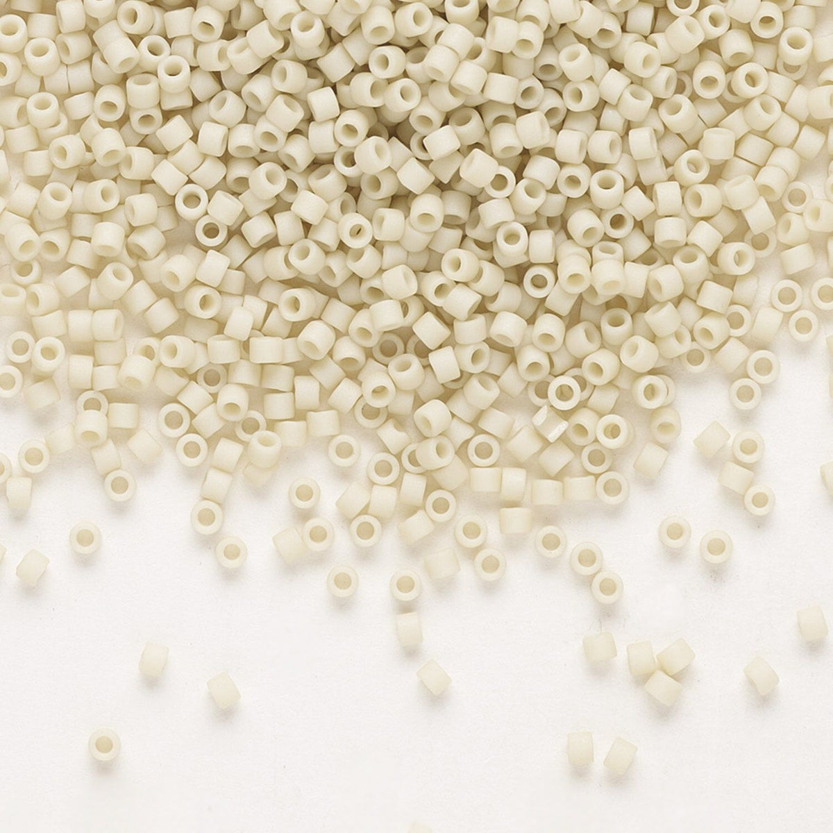 Off-white cylindrical seed beads with hollow centers scattered across a plain white background.