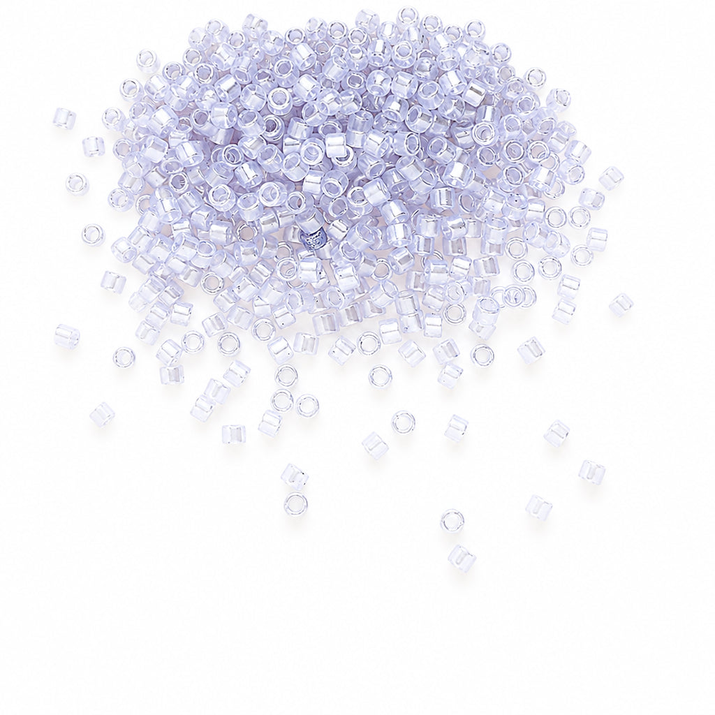 GLASS seed beads with a light lavender-blue tint, scattered across a white background.