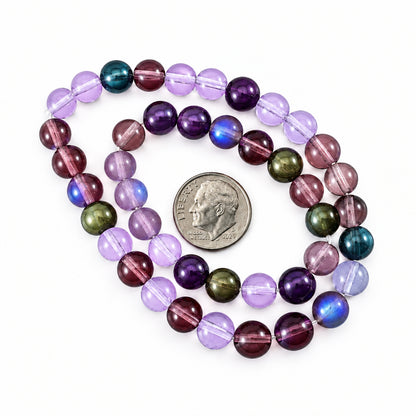 A strand of faceted gemstone beads in purple, lavender, and iridescent metallic tones, shown coiled around a U.S.