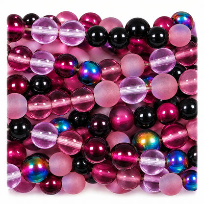 Close-up of a strand of round beads in translucent pink, deep purple, and iridescent tones with some glossy black beads.