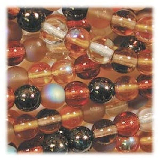 A close-up of round glass beads in warm tones, including amber, orange, translucent clear, and dark black marbled beads, arranged tightly together.