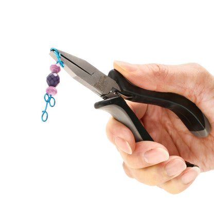 A hand holding a pair of pliers with black handles, which are gripping a small blue metal loop attached to a faceted purple bead and pink beads on a white background.