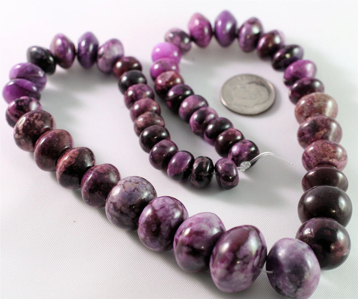Purple and magenta marbled gemstone beads on a white background, with a US quarter coin included for scale.