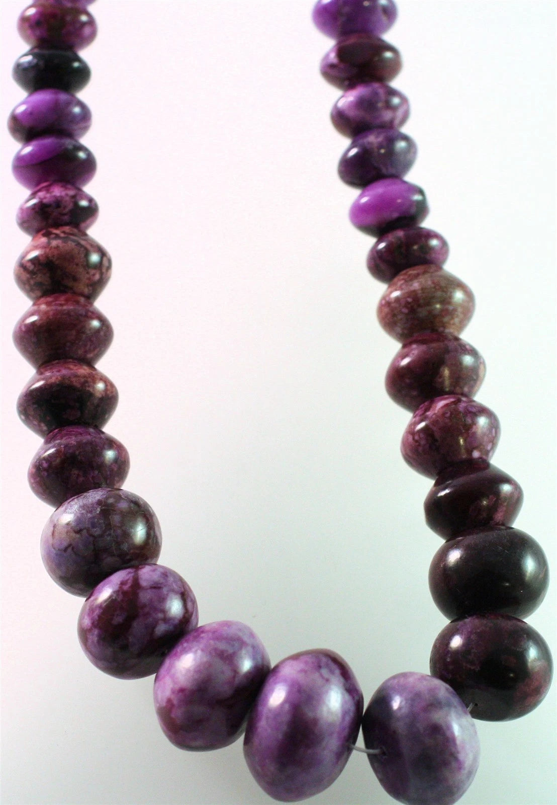 A beaded necklace made of polished oval purple and dark marbled beads, shown against a plain light background.