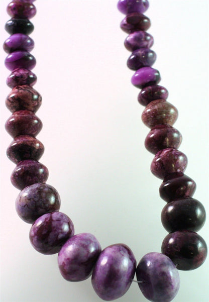 A beaded necklace made of polished oval purple and dark marbled beads, shown against a plain light background.