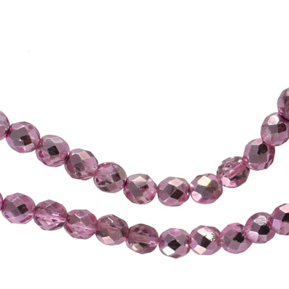 Faceted pink glass beads draped on a clear acrylic stand against a white fabric background.
