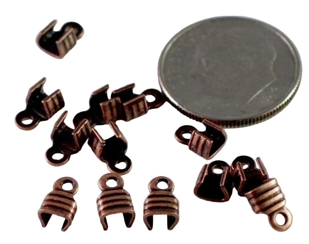 Ten small copper-colored metal jewelry findings or clasp components arranged on a white background next to a silver coin for scale.