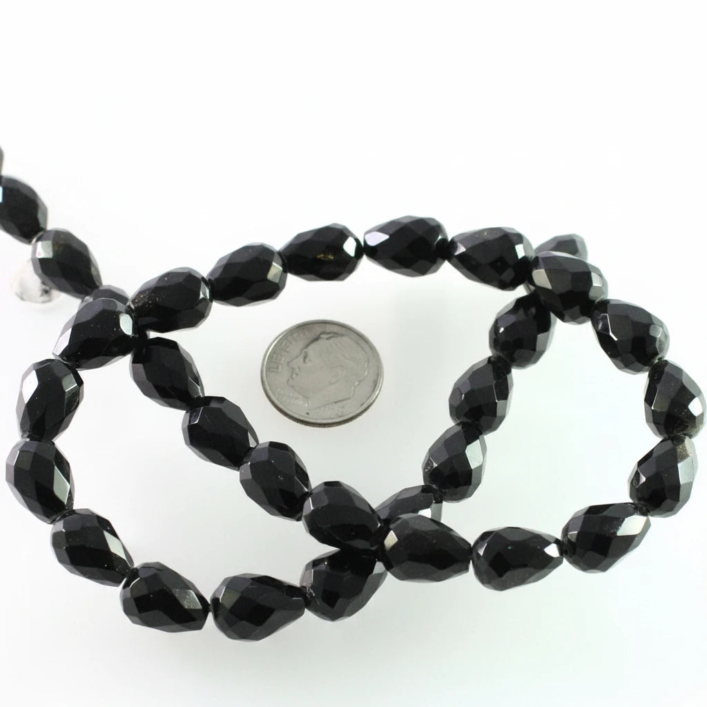 Faceted black beads on a strand, shown with a US quarter coin for scale on a white background.