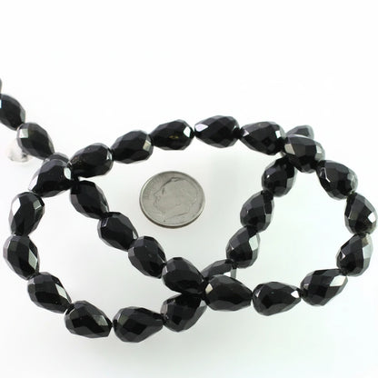 Faceted black beads on a strand, shown with a US quarter coin for scale on a white background.