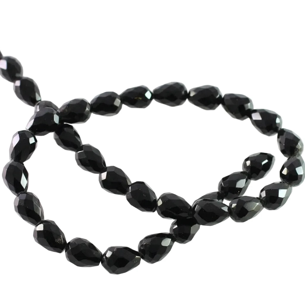Faceted black glass beads arranged in a loose circle on a plain white background.