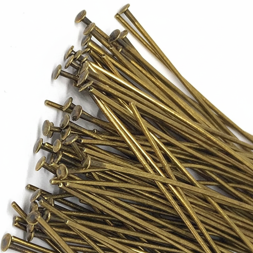 A pile of brass-colored metal nail tips with long straight pins, arranged on a plain white background.