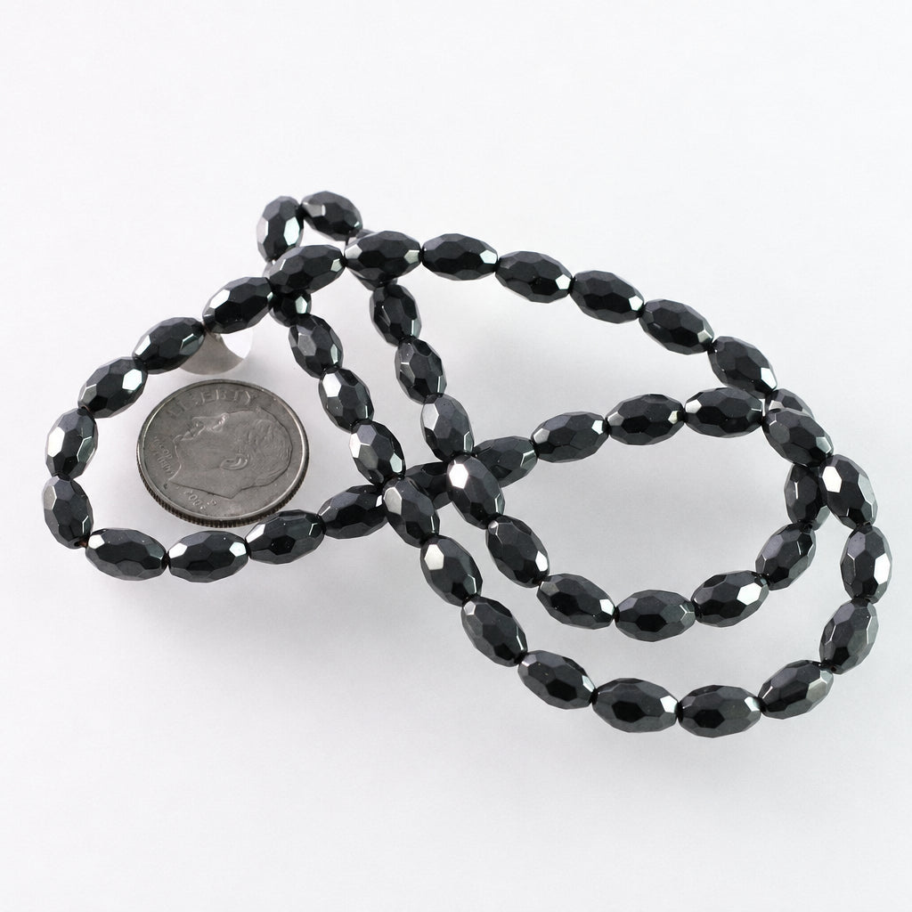 Faceted black beads on a white background with a US quarter coin for scale.