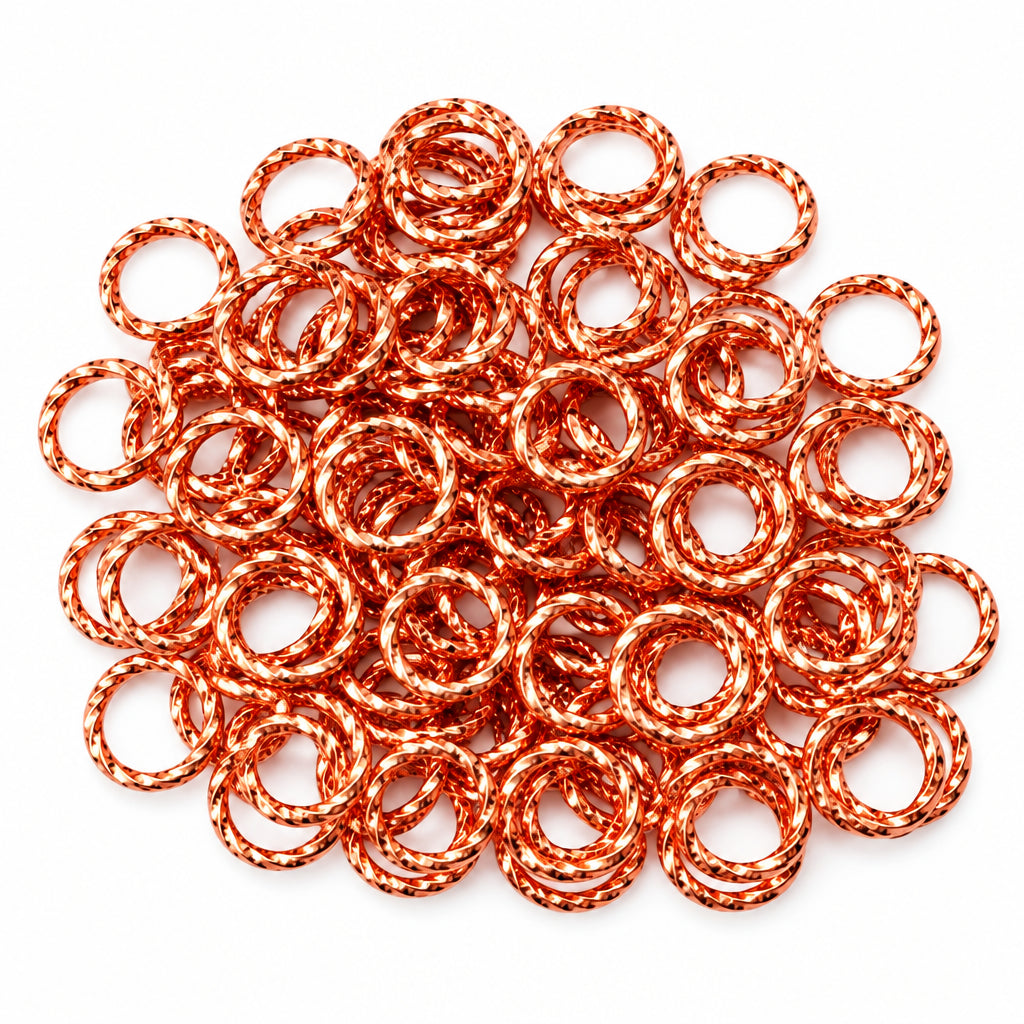 A pile of copper-colored metal JUMP ring links, shown with a U.S. dime for scale on a plain light background.
