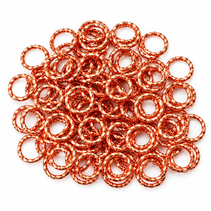 A pile of copper-colored metal JUMP ring links, shown with a U.S. dime for scale on a plain light background.