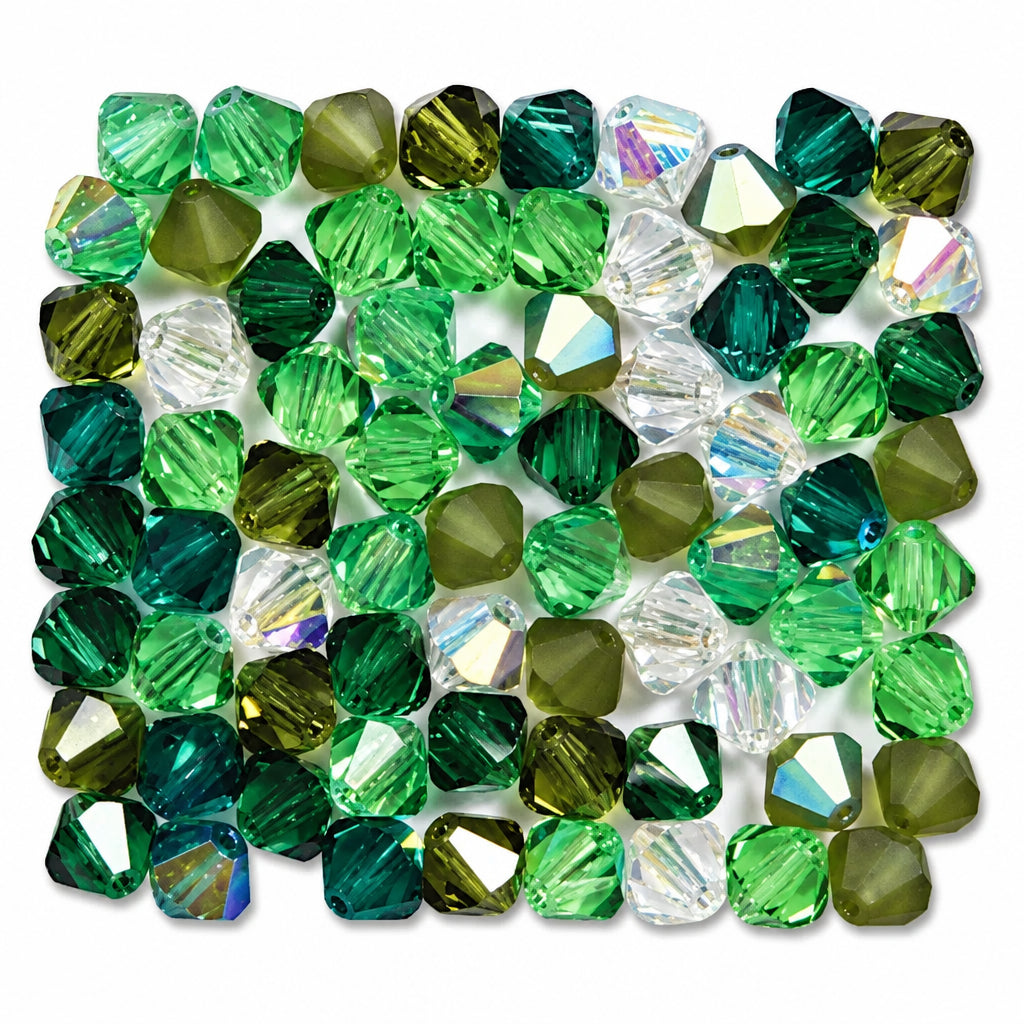 A collection of faceted glass beads in various shades of green, from light mint to deep forest green, with some iridescent AB beads reflecting pastel colors, arranged on a white background.