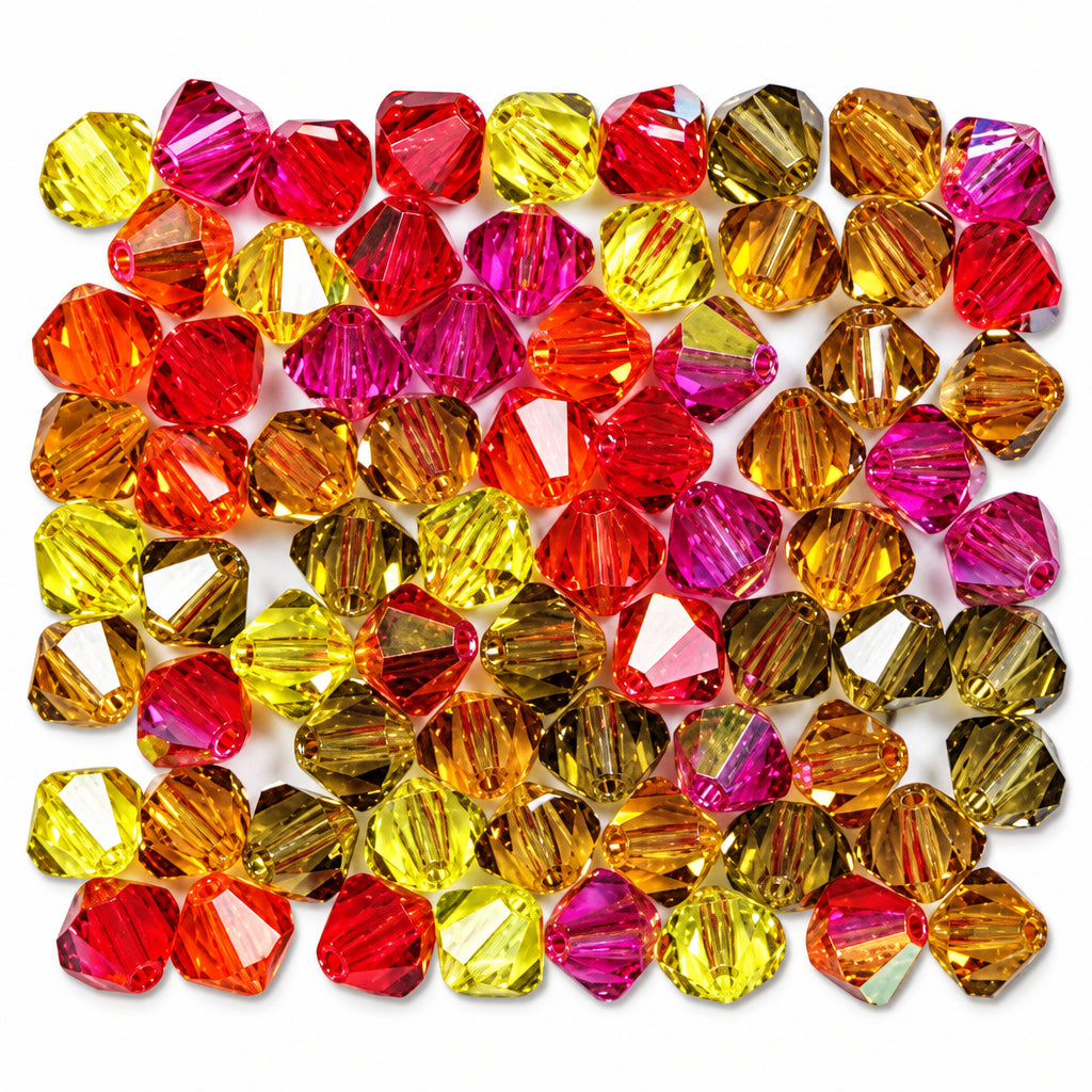 A pile of faceted crystal beads in assorted warm colors including red, orange, pink, yellow, and amber, arranged on a plain white background.