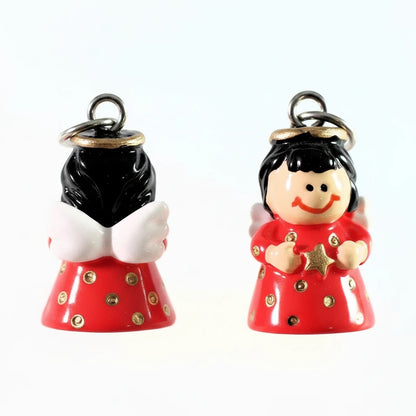 Two small glossy angel figurines on a plain white background. One angel faces forward with black hair, white wings, a red dress with gold polka dots, and a silver hanging loop.