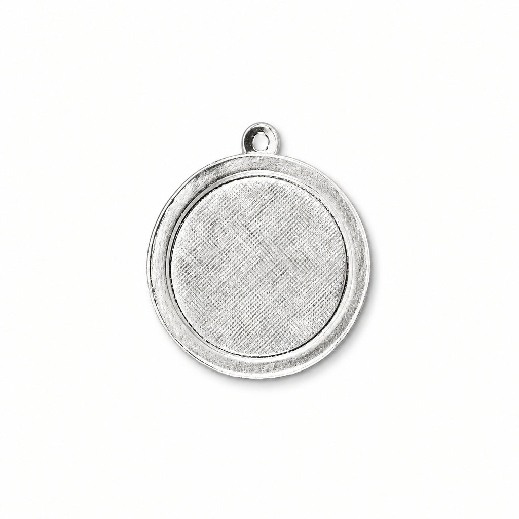 A round silver-toned metal pendant or charm blank with a textured center and a small loop at the top, shown on a plain white background.