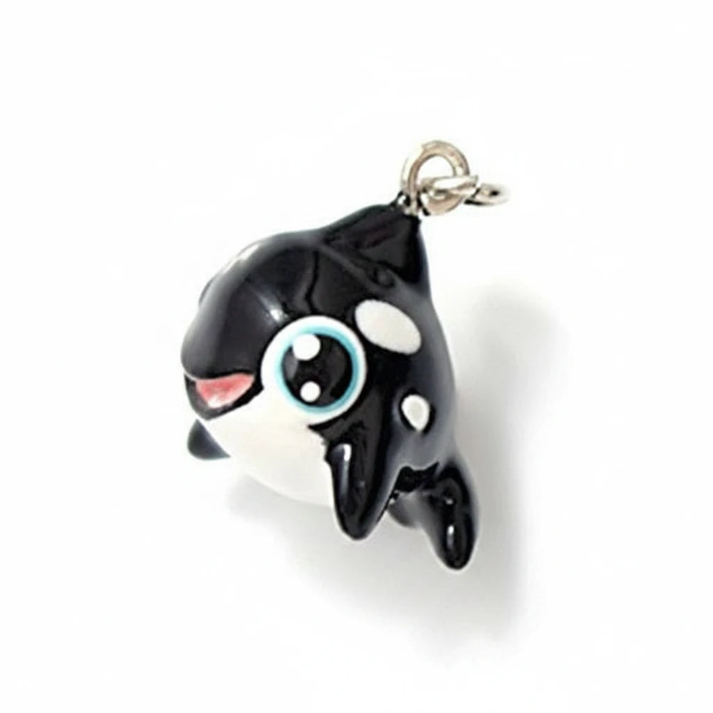 A small black and white cartoon orca charm with a silver clasp, shown on a white background with a '1/2 inch line' size reference below.