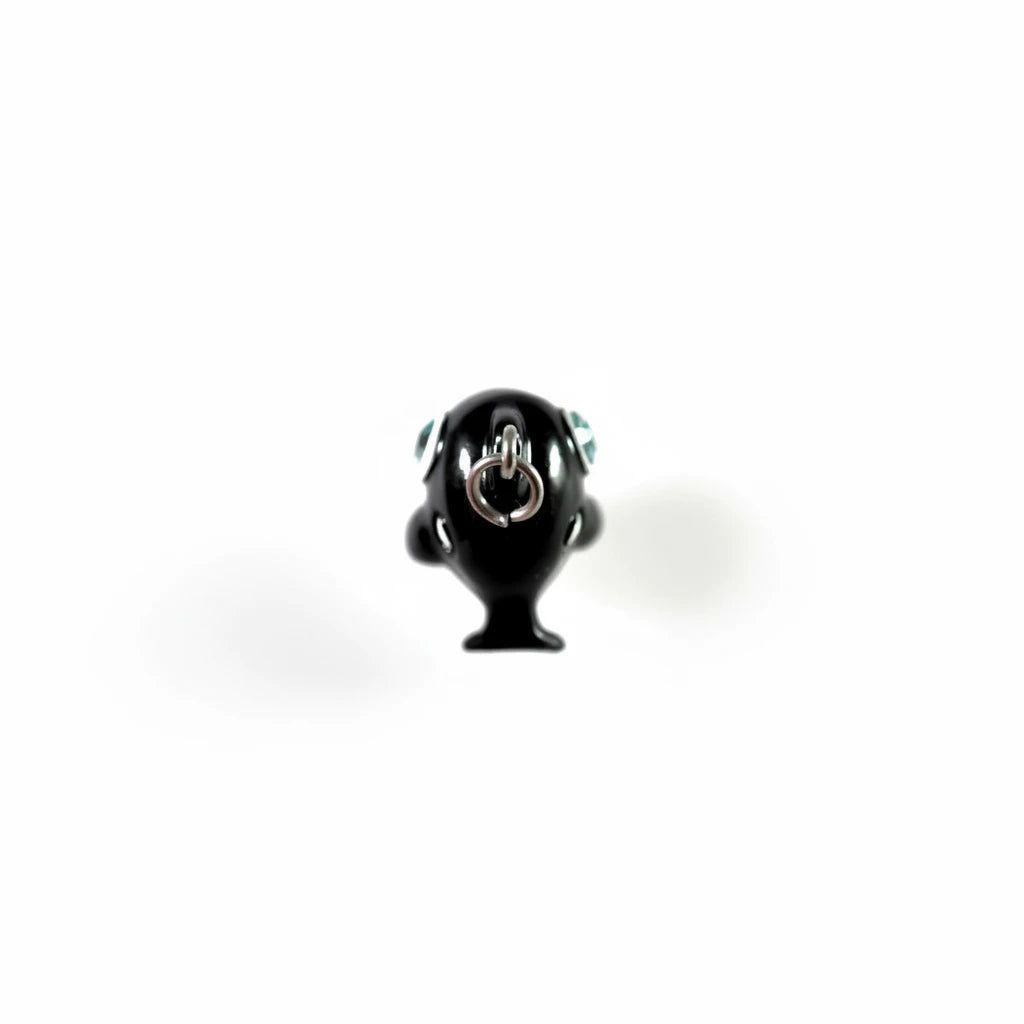 A glossy black pendant shaped like a stylized character head with a silver metal ring clasp on top, shown against a plain light background.