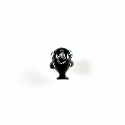A glossy black pendant shaped like a stylized character head with a silver metal ring clasp on top, shown against a plain light background.