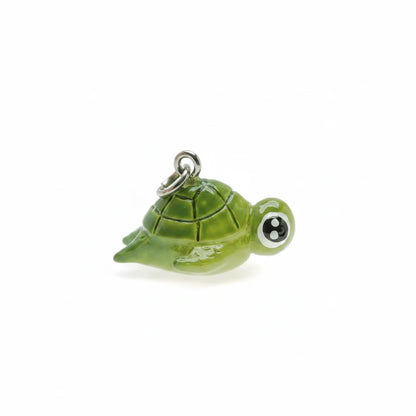 A glossy green ceramic turtle charm with a silver metal loop at the top, shown on a plain white background.