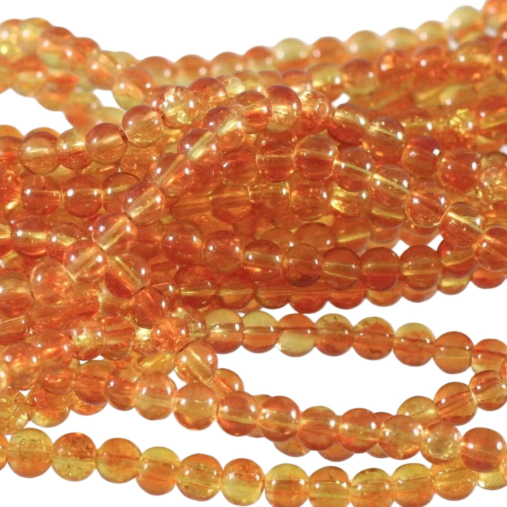 Multiple strands of small, round, translucent amber-orange beads arranged closely together on a white background.