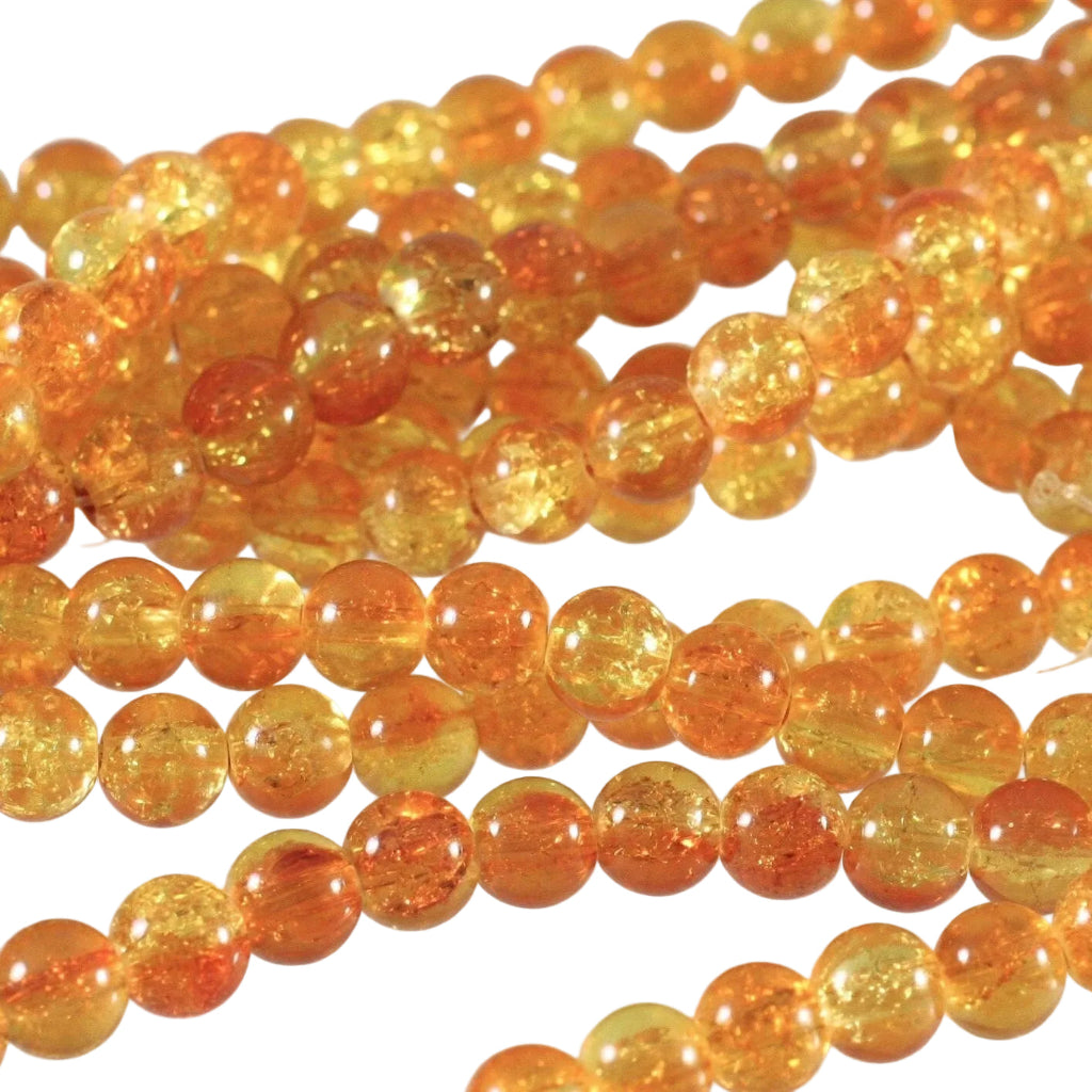 Close-up of strands of round amber-orange glass beads with visible internal glitter and translucent yellow-orange tones on a light background.