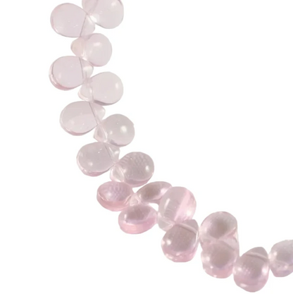 A strand of translucent light pink round beads draped diagonally across a white studio background.